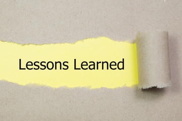 lessons learned word written under brown torn paper