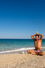 Fototapeta na wymiar Adult male in the morning practice yoga on the beach
