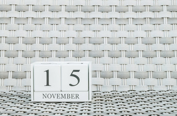 Closeup surface white wooden calendar with black 15 november word on blurred weave wood chair...