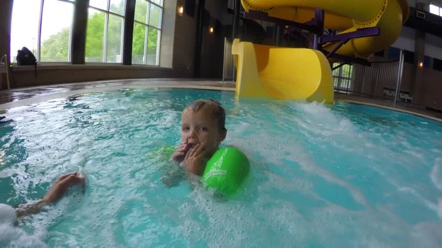 A boy goes down a waterslide in pool