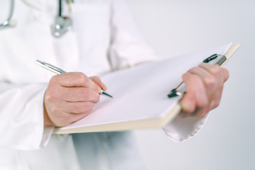 Fototapeta Female doctor in white uniform writing on clipboard paper obraz