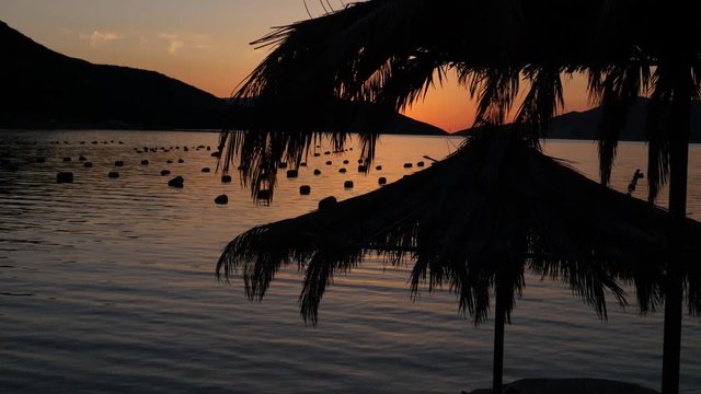 Footage of a calm beach at a sunset with two parasols nearby...