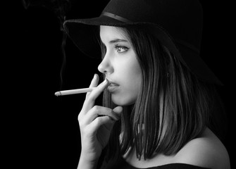 Portrait of the beautiful elegant girl smoking cigarette isolated on black background