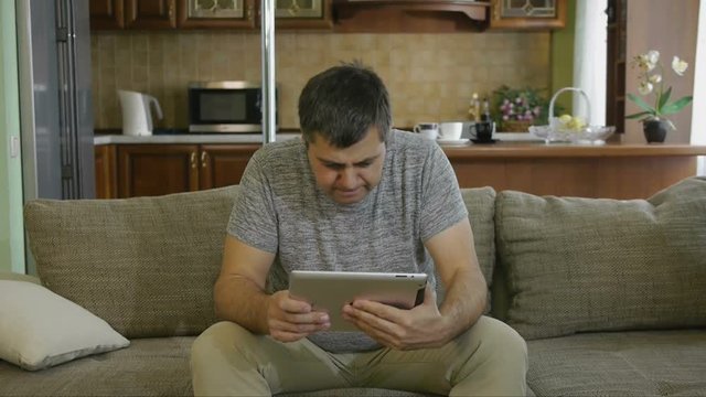 Male 40 - 45 years sitting on the couch with digital tablet
