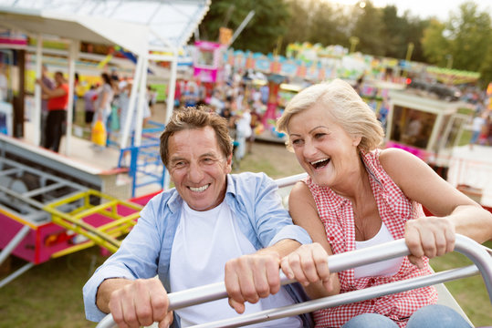 Senior Couple On A Ride In Amusement Park