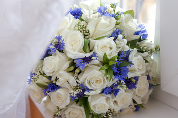 beautiful bouquet of white roses and cornflowers, rests on the w