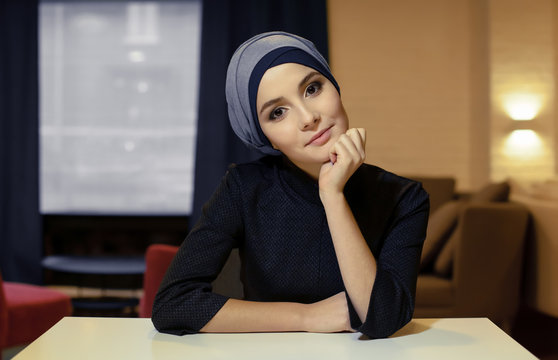portrait of a beautiful young Muslim woman sitting at a table