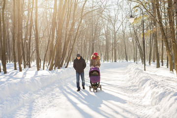 Young family walking with baby stroller in park