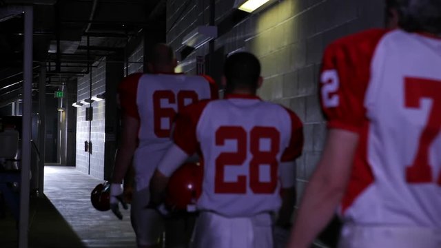 Football players walk back to their locker room down the tunnel after a game