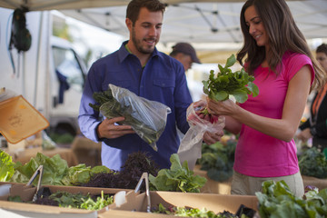 Young couple shopping for flowers and produce at a farmer's market in San Diego, California.