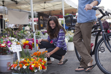 Young couple shopping for flowers and produce at a farmer's market in San Diego, California.