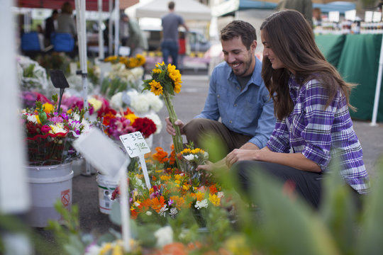 Young couple shopping for flowers and produce at a farmer's market in San Diego, California.
