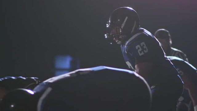 A football player jumps over the line and tackles the quarterback