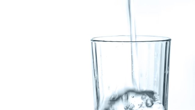 Pouring clean water into the glass. Closeup on white background. Slow motion
