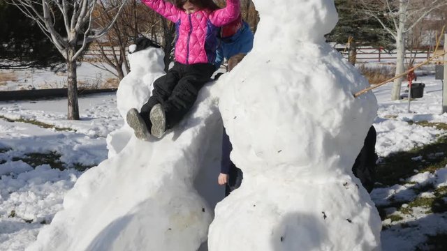 A family makes snow men and a slide from snow