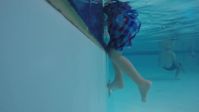 Underwater shot of a little boy climbing out at the pool