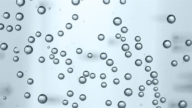 Sparkling water in glass. Bubbles rising up and exploding
