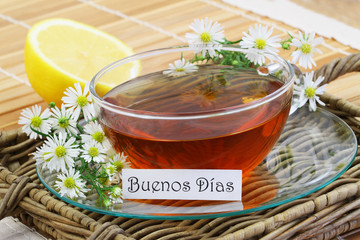Buenos dias (which means Good morning in Spanish) with cup of chamomile tea and fresh chamomile flowers
