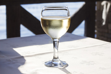 Glass of white wine on a table at sunset on the sea