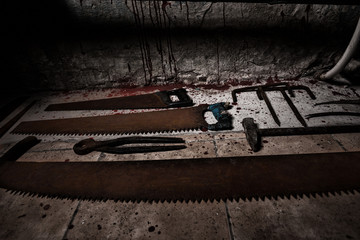 Saws, sickles and other devices on the bloody floor  in basement