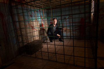 Handsome male imprisoned in a metal cage with a blood splattered