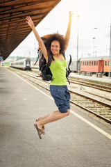 Happy female tourist jumping at the railway station
