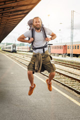 Happy male tourist jumping at the railway station