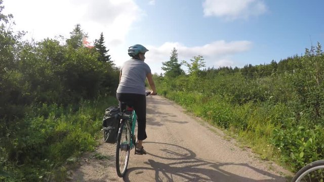 Fun shot of a woman biking in green forest on bike trail