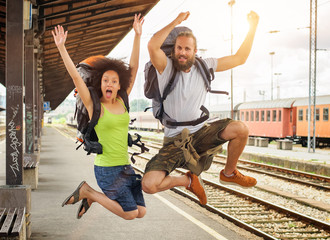Two happy tourists jumping at the railway station