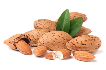 heap of almonds in their skins and peeled with leaf isolated on white background