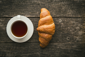 Tasty buttery croissant and cup of tea.