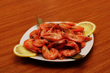 Tasty cooked shrimp lying on a plate with lemon and a variety of spices.