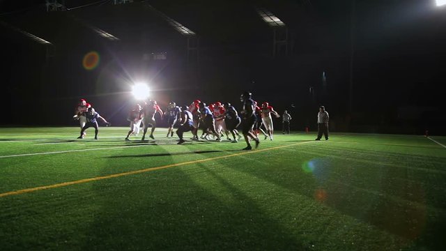 Wide shot of a football player running past defenders and scoring a touchdown