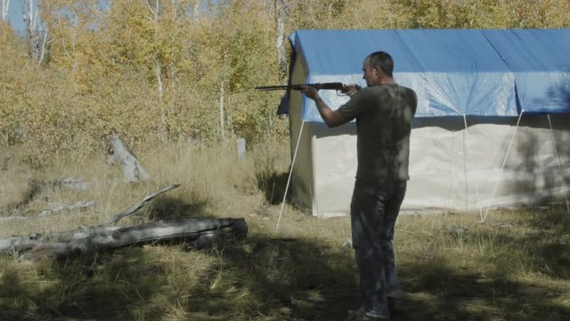A man shooting a rifle while camping