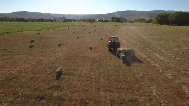 Aerial cool shot as a the tractor cuts and bails hay
