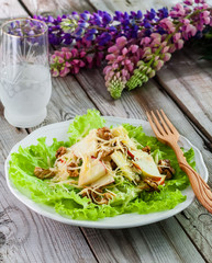 Apple, cheese, walnut, lettuce salad on wooden background.