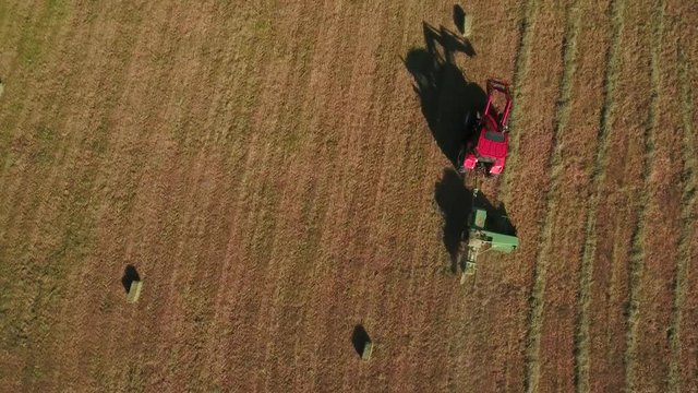 Aerial timelapse as a farmer cuts and bails hay with tractor