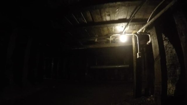 A camera moving shot through dark coal mine in glace bay with tourists