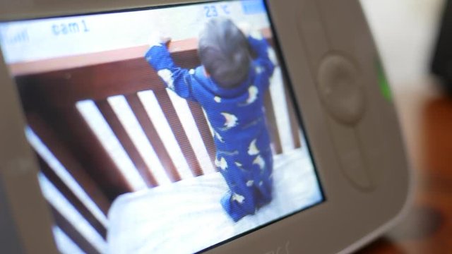 Watching a cute baby playing in his crib on a monitor