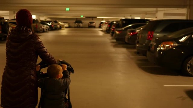 A mother and toddler push stroller through parking garage