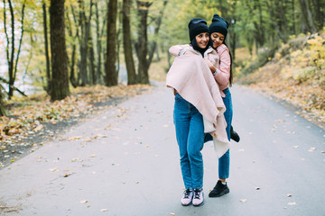 Two stylish, sexy and fashionable girls posing in autumn park