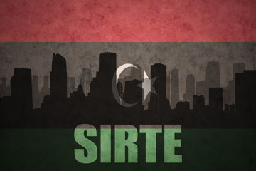 Fototapeta na wymiar abstract silhouette of the city with text Sirte at the vintage libyan flag