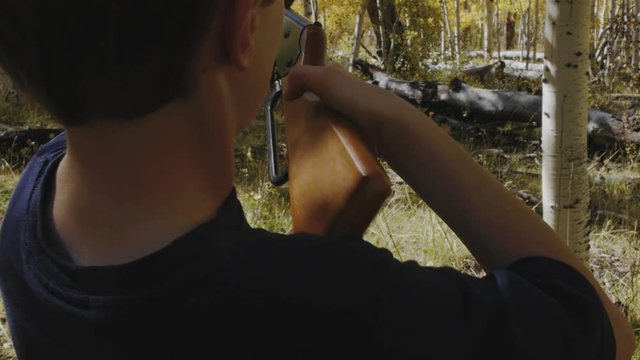 Boy shooting a bb gun while camping