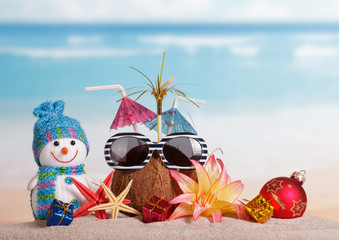 Coconut, sunglasses, snowman, starfish, ball and gifts flower against sea.