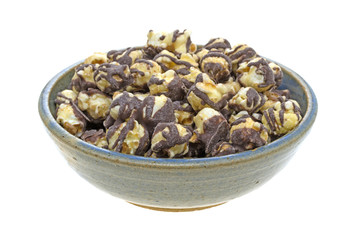 Fudge drizzled popcorn in an old bowl side view isolated on a white background.