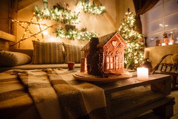 Homemade gingerbread house on background room decorated for Christmas.