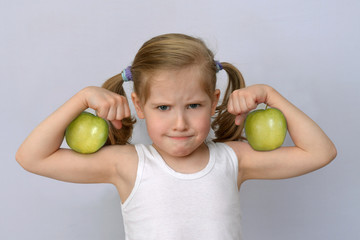 little girl with green apples showing biceps.