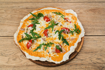 Cheese pizza with tomato and fish decorated with ruccola and served on a wooden round tray
