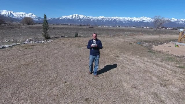 Aerial shot of man using remote to fly drone