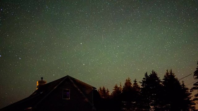 A timelapse shot of stars rotating above a house at night as it then turns to morning